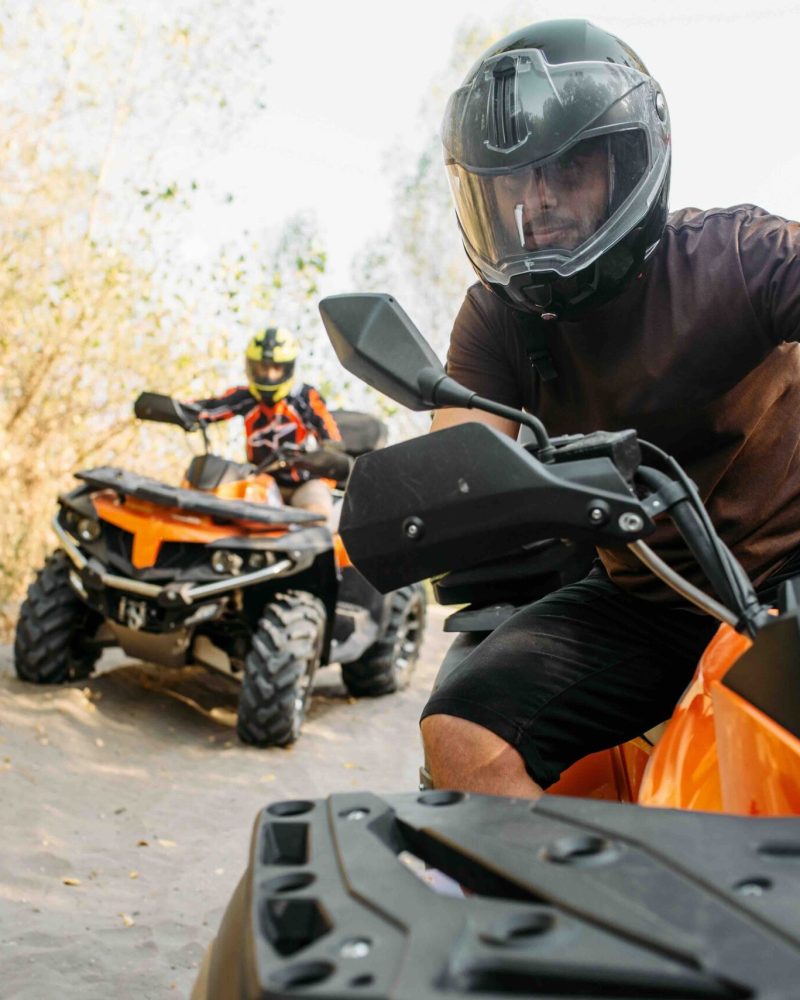 Two quad bike riders in helmets travels in forest, front view. Riding on atv, extreme sport and travelling, quadbike adventure