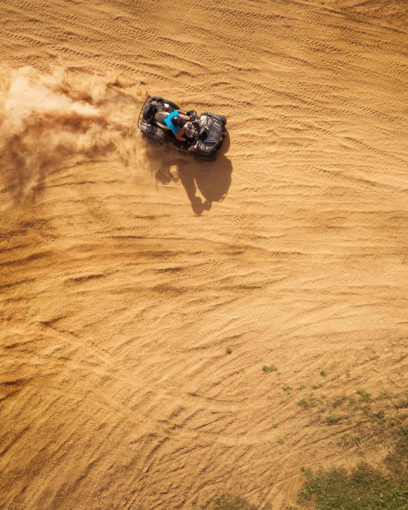 Aerial view of quad bikes driving in the sand .
