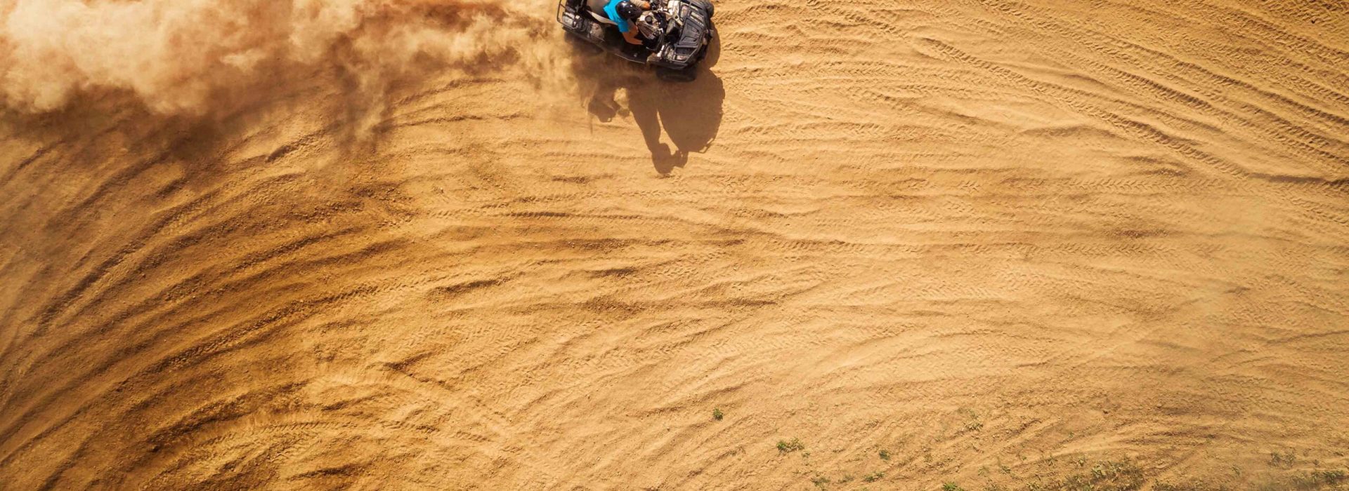 Aerial view of quad bikes driving in the sand .