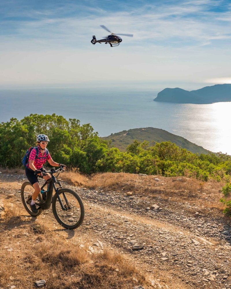 nice woman riding her electric mountain bike during sunset on the coastline above the mediterranean sea on the Island of Elba in the tuscan Archipelago, Tuscany, Italy