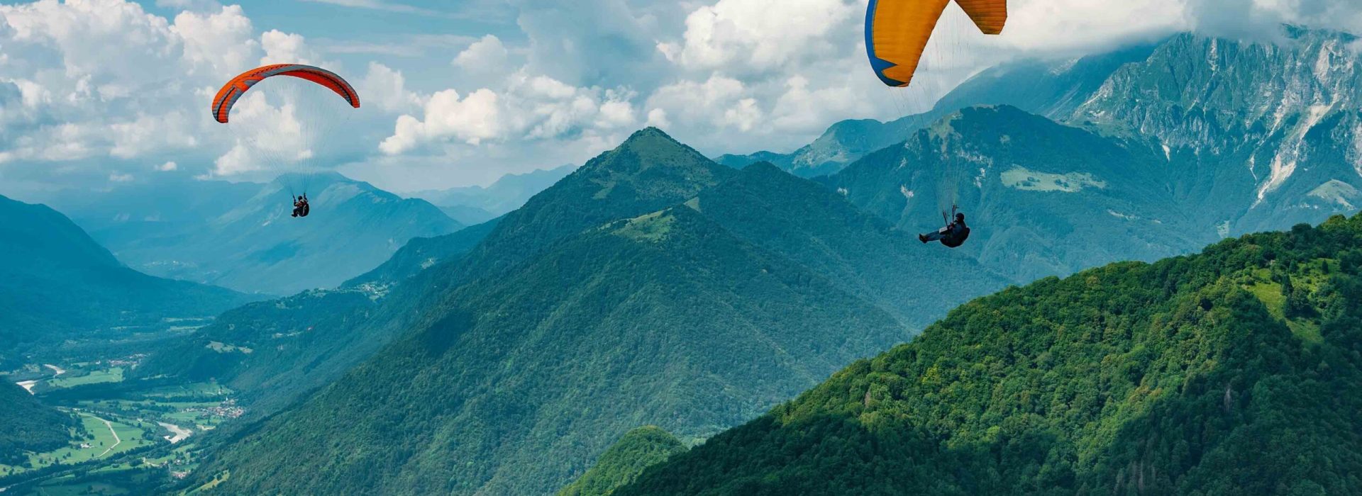 Colorful paraglider wings fly in the mountains near Tolmin, Slovenia. Soca valley, the Europe popular tourist destination, Mecca for extreme sports and active lifestyle.